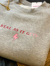 Load image into Gallery viewer, Grey-sweatshirt-close-up-slogan-Real-as-it-gets-with-pink-thunderbolt-detail
